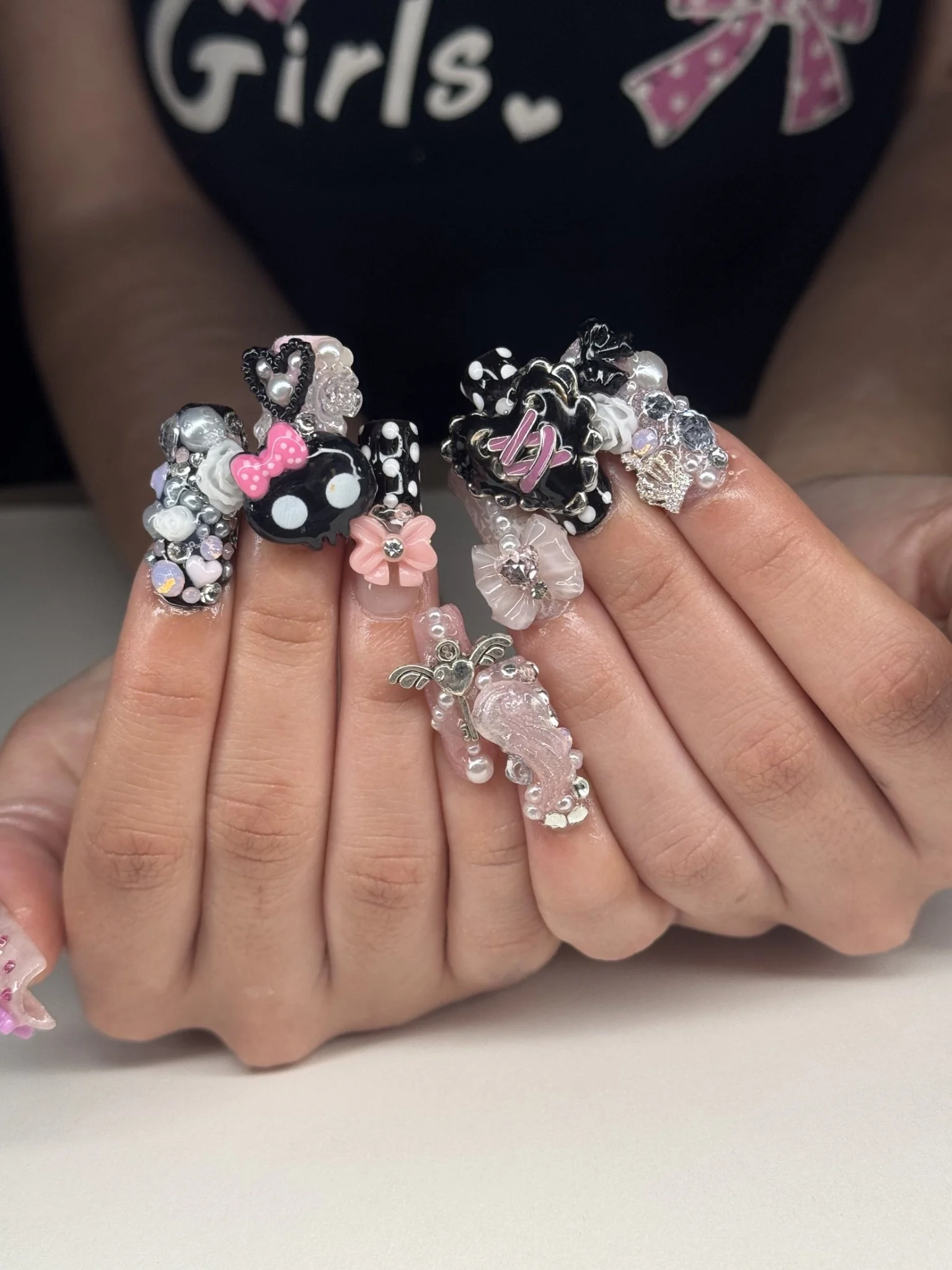 Black, pink and silver three-dimensional nail art with bows, pearls and playful character charms by Studio Vitalesca